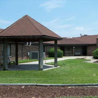 A view of a residential building with a gazebo and well-maintained lawn under clear blue skies.