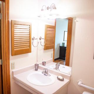A view of a clean and organized bathroom featuring a sink, mirror, and light fixtures.