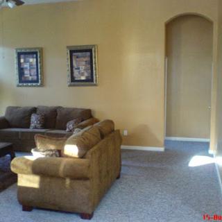 A cozy living room featuring a brown couch and decorative wall art on yellow-painted walls.