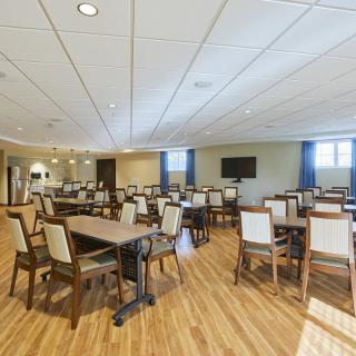 A spacious, well-lit meeting room with multiple tables and chairs arranged in rows.