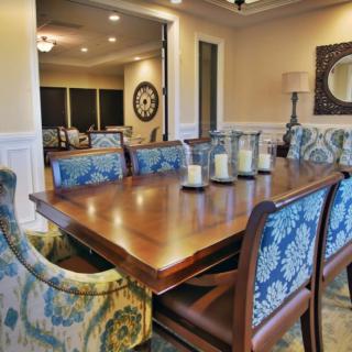 A beautifully decorated dining room with a wooden table, blue-patterned chairs, and elegant candles.