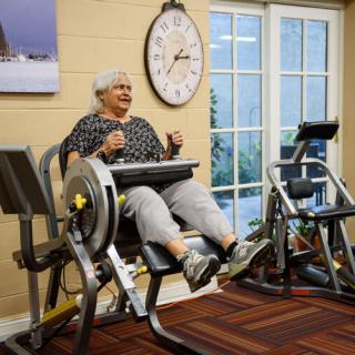 An elderly person exercising on fitness machines in a gym.