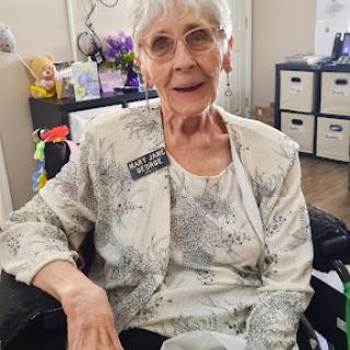 A cheerful elderly woman sitting in a wheelchair, enjoying her day indoors.