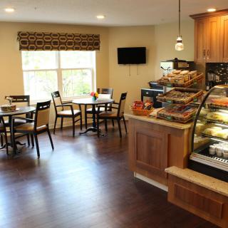 Cozy caf interior with tables, chairs, and a display case filled with pastries.