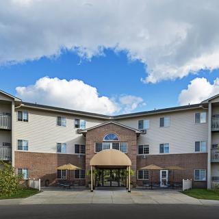 A multi-story residential apartment complex with a brick facade under a partly cloudy sky.