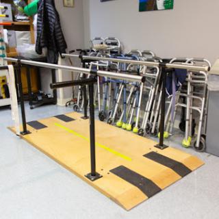 An exercise setup featuring parallel bars for rehabilitation and balance training, alongside various walking aids.