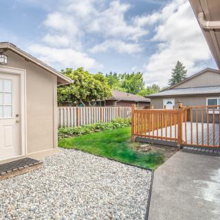 A backyard with a small shed, grassy area, and surrounding fence on a sunny day.