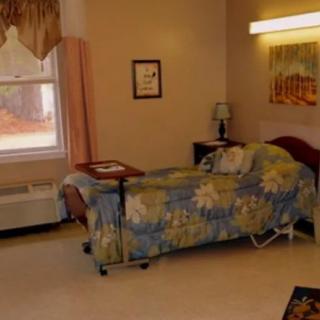 A cozy bedroom with a floral patterned bedspread and a small bedside lamp.