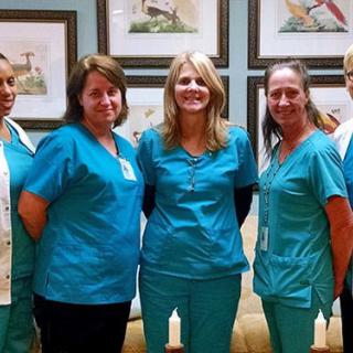 A group of healthcare professionals in blue scrubs posing for a team photo.