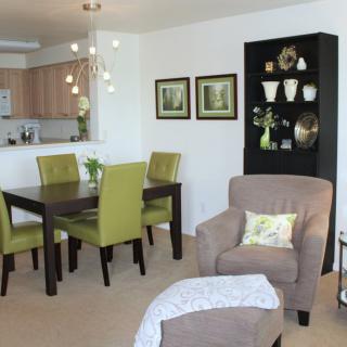 A modern open-plan dining and living area featuring green chairs and stylish decor.