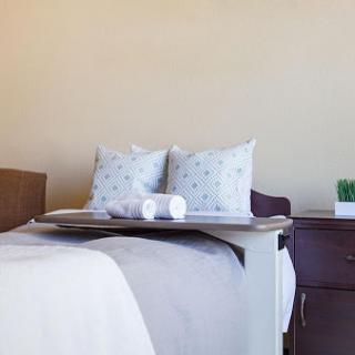 A cozy bedroom setup featuring neatly arranged pillows and a bedside table.