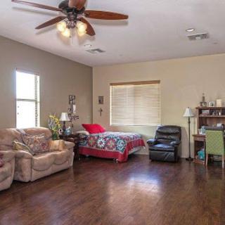 A cozy living room featuring a mix of comfortable seating and a bed, illuminated by natural light.