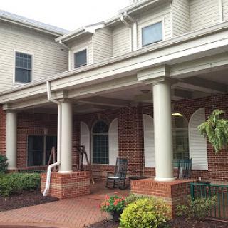 A charming residential building featuring a spacious porch supported by elegant columns.