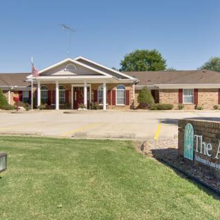 A single-story brick building with a prominent entrance sign, surrounded by a neatly maintained lawn.