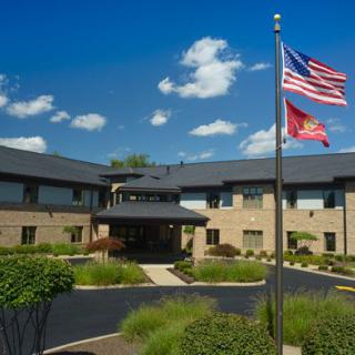 A modern building with flags flying in the foreground under a clear blue sky.