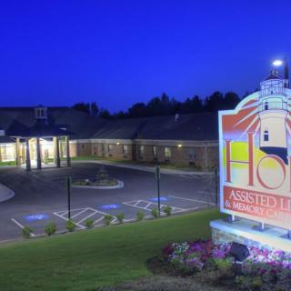 Illuminated building and sign at night with a parking area.