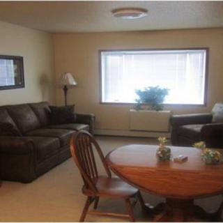 A cozy living room with a couch, armchair, and a table set near a large window.