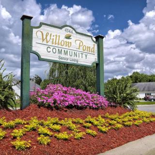 A beautifully landscaped community sign for Willow Pond Communities against a cloudy sky.