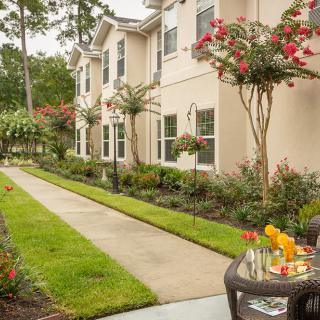 A charming residential pathway lined with vibrant flowers and outdoor seating.
