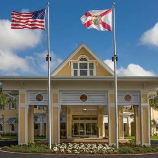 A building entrance with the United States and Florida state flags flying prominently.