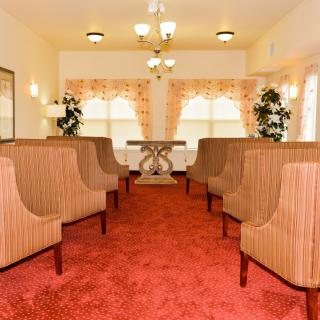 A cozy waiting area with lined-up chairs, warm lighting, and large windows.