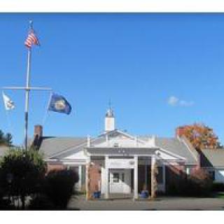A building with multiple flags displayed in front under a clear blue sky.