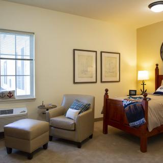 A cozy bedroom featuring a wooden bed, comfortable seating area, and warm lighting.