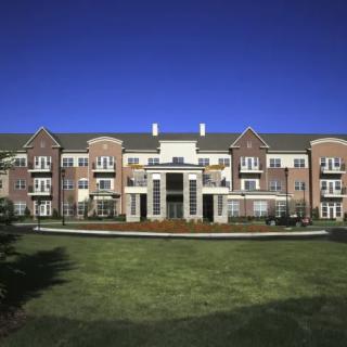 A large residential building with a well-maintained lawn and clear blue sky.