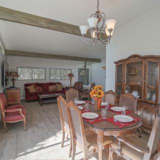 A cozy dining and living area featuring a wooden dining table set, a chandelier, and a comfortable sofa.