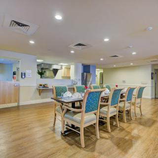 A modern dining room with a long table surrounded by chairs on a wooden floor.