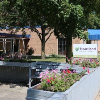 A welcoming outdoor area featuring a building, greenery, and colorful flowers.