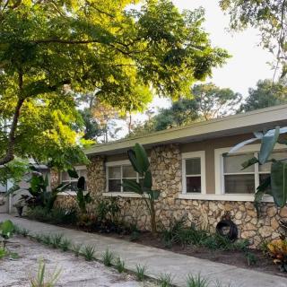 A cozy stone house surrounded by lush green trees and sunlight.
