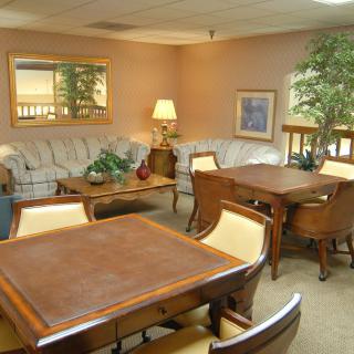 A cozy living room with a large sofa, coffee table, and a dining area featuring wooden tables and chairs.