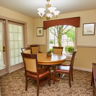A cozy dining room with a round table, upholstered chairs, and a chandelier.
