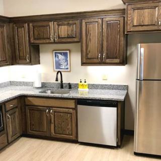 A modern kitchen with wooden cabinets, stainless steel appliances, and a well-organized countertop.