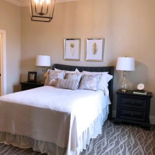 A cozy and elegant bedroom featuring a neatly made bed, stylish nightstands with lamps, and decorative wall art.