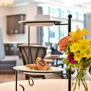 A beautifully presented dish on a tiered stand with vibrant flowers enhancing the elegant ambiance of the restaurant.
