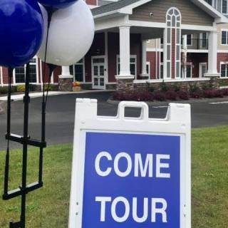 A sign with balloons invites people to tour the building.