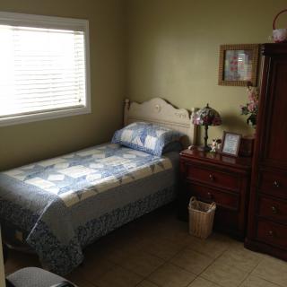 A cozy bedroom with a single bed, nightstand, and cabinet.