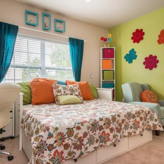 A vibrant and colorful bedroom with floral designs and decorative wall art.