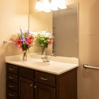A well-lit bathroom with a floral arrangement on the vanity.