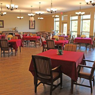 A spacious dining room with elegant decor and red tablecloths on the tables.