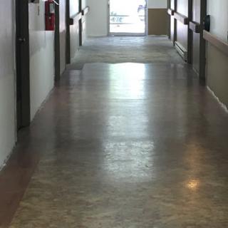 A long, empty hallway with polished floors and light streaming in from the entrance.