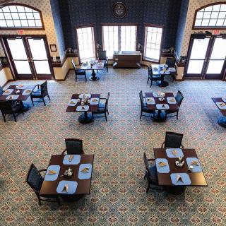 An empty restaurant dining room with neatly arranged tables and chairs.