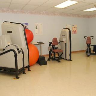 A fitness room equipped with various exercise machines and stability balls.