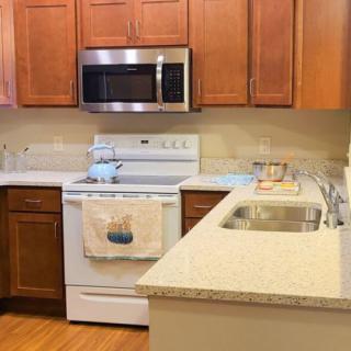 A modern kitchen with wooden cabinets, granite countertops, and standard appliances.