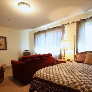 A cozy bedroom with a bed, couch, and warm lighting.