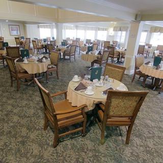 A spacious dining area with multiple tables and chairs, elegantly set for service.
