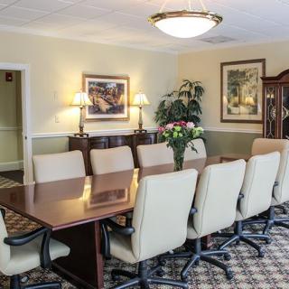 A well-furnished conference room with a long table and office chairs surrounded by wall decor and plants.