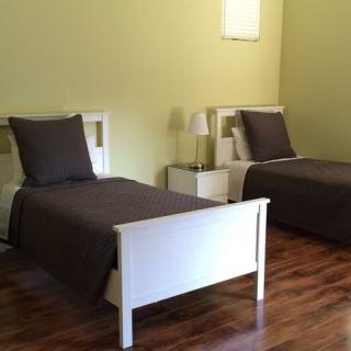 A minimalist bedroom with two twin beds and wooden flooring.